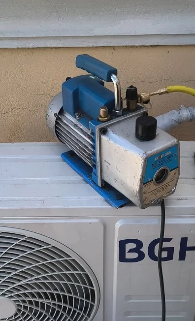 Bomba de vacío conectada a las cañerías de cobre de un aire acondicionado antes de cargar el gas